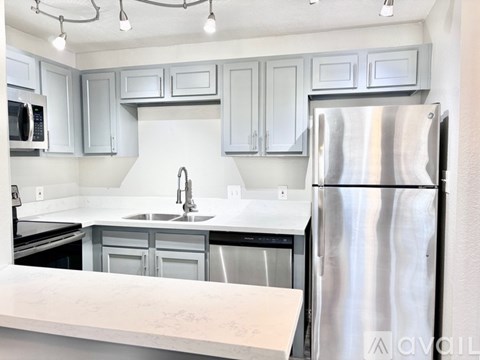 A kitchen with a stainless steel refrigerator and white countertops.