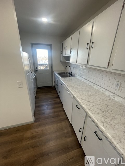 A kitchen with white cabinets and a marble countertop.