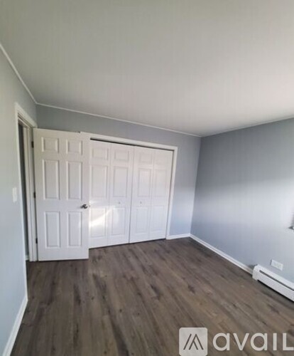 A room with a white door and wooden flooring.