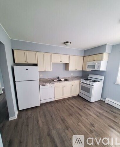 A kitchen with white appliances and wooden floors.