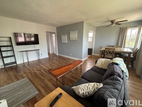 A living room with a black couch and a wooden coffee table.