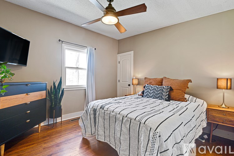 A bedroom with a bed, dresser, and ceiling fan.