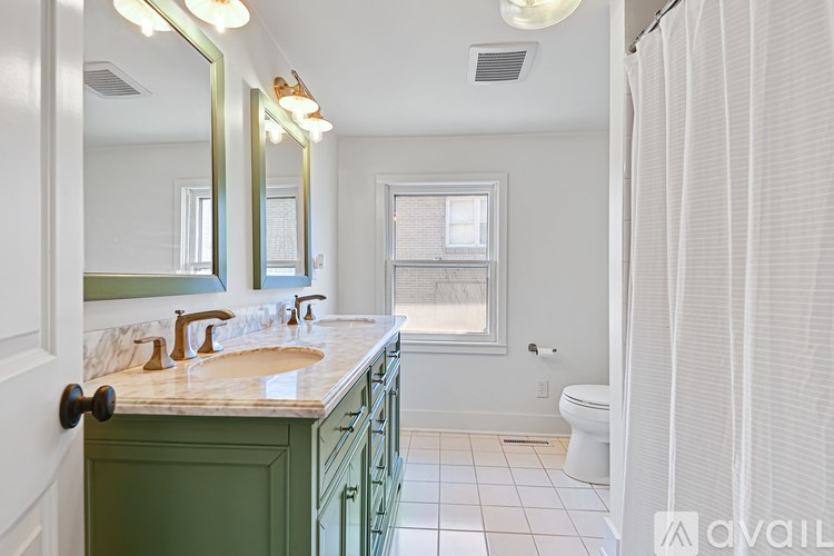 A bathroom with green cabinets and a marble countertop.