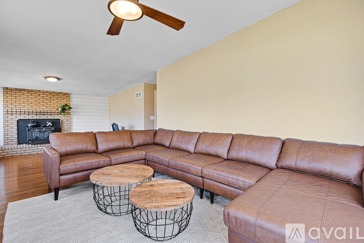 A living room with a brown leather sectional sofa and a wooden coffee table.