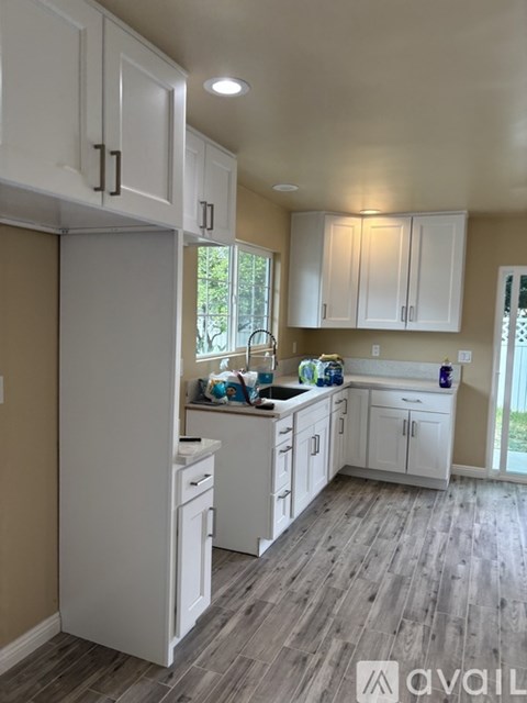 A kitchen with white cabinets and a wooden floor.