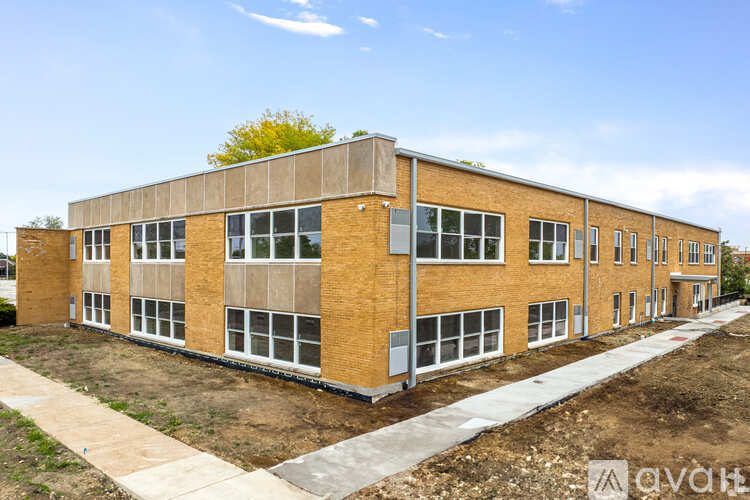 A large, unfinished brick building with a flat roof and a walkway in front.