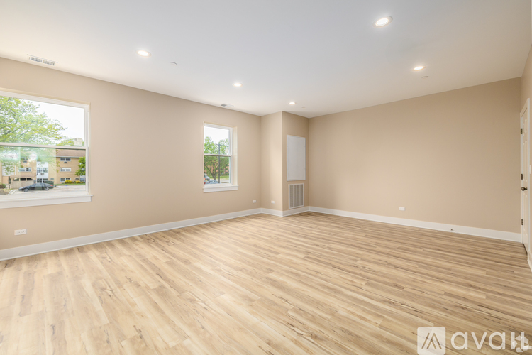 A spacious room with wooden flooring and a large window.
