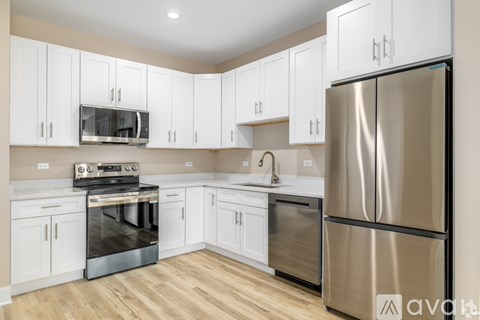 A kitchen with white cabinets and a stainless steel refrigerator.