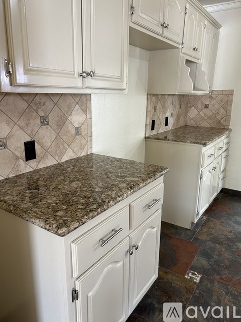 A kitchen with granite countertops and white cabinets.