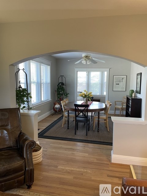 A living room with a brown leather chair and a round table with chairs around it.