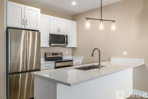 A modern kitchen with a stainless steel refrigerator, microwave, and a sink with a faucet.