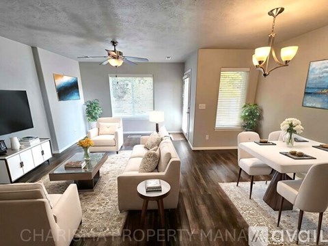 A well-lit living room with a white sofa set and a wooden coffee table.