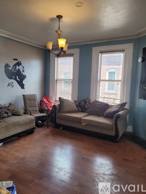 A living room with a couch, chairs, and a painting on the wall.
