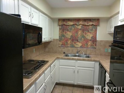 A kitchen with white cabinets and a black refrigerator.