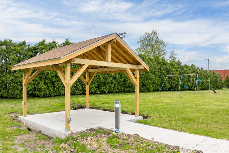 A wooden pavilion with a roof and a post box in front of it.