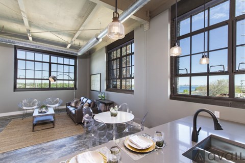 A modern kitchen and living room with a dining table set for two.