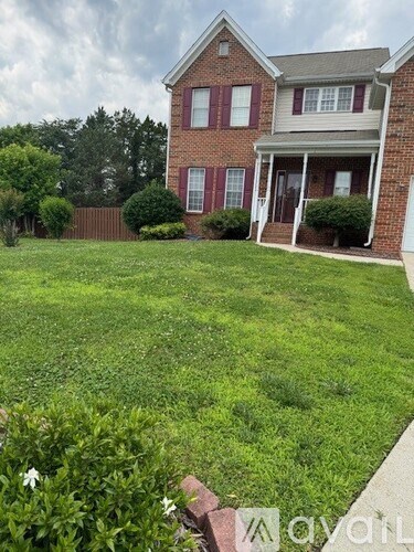 A brick house with a green lawn in front.