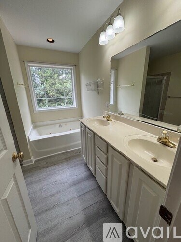 A bathroom with a tub, sink, and mirror.