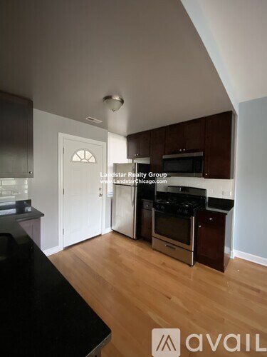 A kitchen with a black counter top and wooden floors.