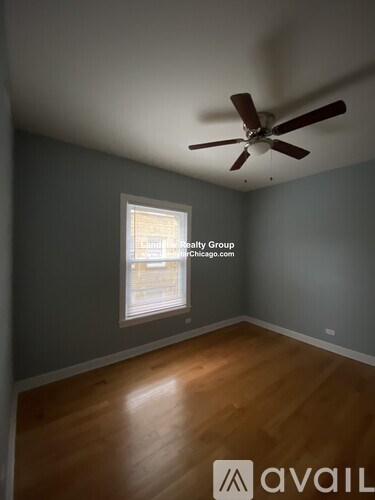 A room with a fan and a window showing a view of a building.