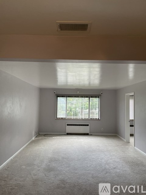 A spacious room with a window and a radiator on the wall.