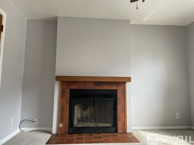 A living room with a fireplace and a ceiling fan.