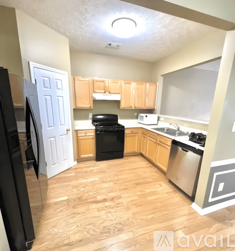 A kitchen with wooden floors and a black refrigerator.