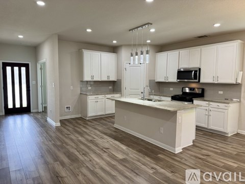 A modern kitchen with white cabinets and a wooden floor.