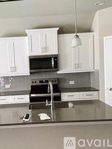 A kitchen with white cabinets and a grey counter top.