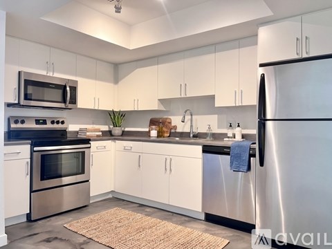 A kitchen with white cabinets and a black fridge.