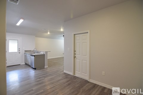 A kitchen area with a sink and a refrigerator in a room with wooden flooring.