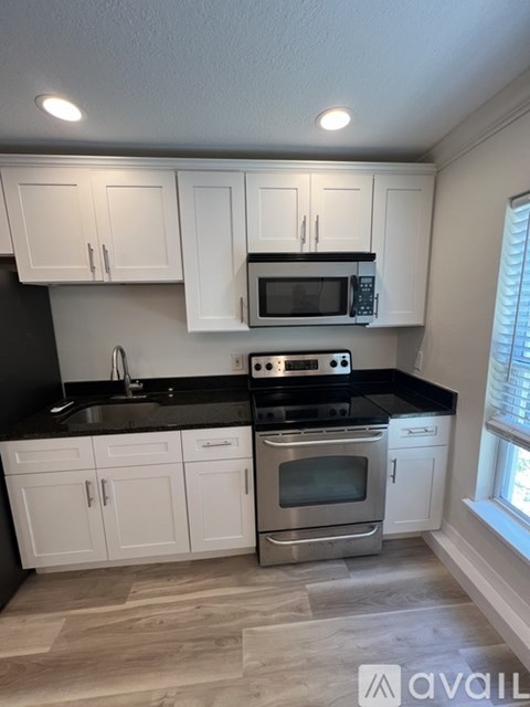 A kitchen with white cabinets and black countertops.