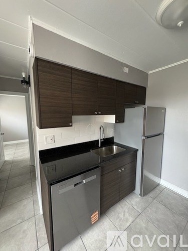 A kitchen with a sink, refrigerator, and cabinets.