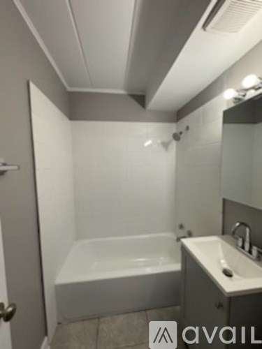 A bathroom with a bathtub, sink, and mirror.