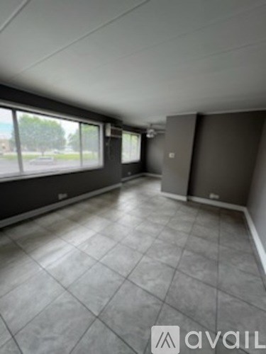 A room with grey tiled flooring and large windows.