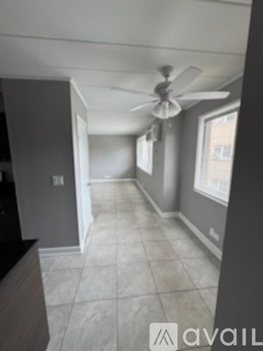 A room with a ceiling fan and tile flooring.