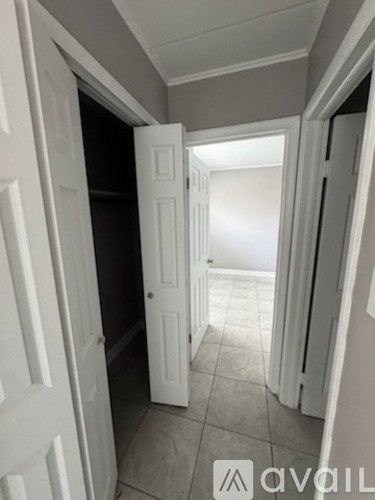 A hallway with white doors and tiled floors.