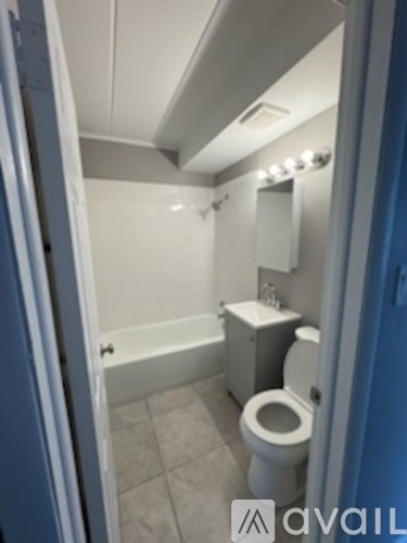A white toilet in a small bathroom with a white bathtub.