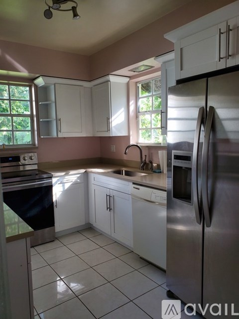 A kitchen with white cabinets and a stainless steel refrigerator.