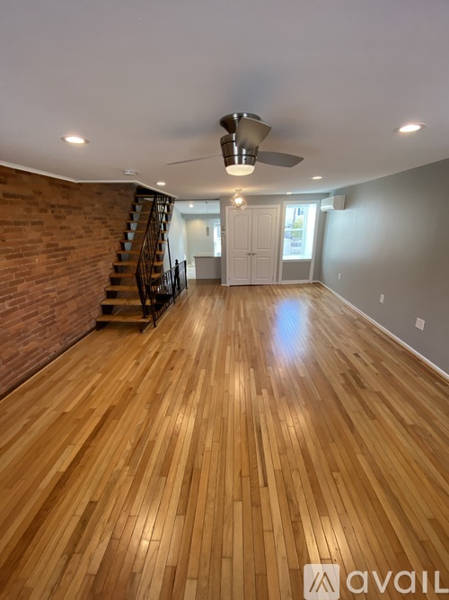A room with wooden flooring and a brick wall.