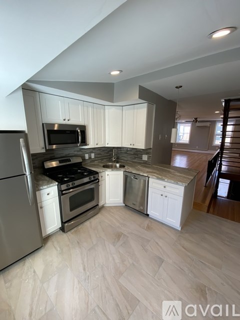 A kitchen with white cabinets and a stainless steel refrigerator.