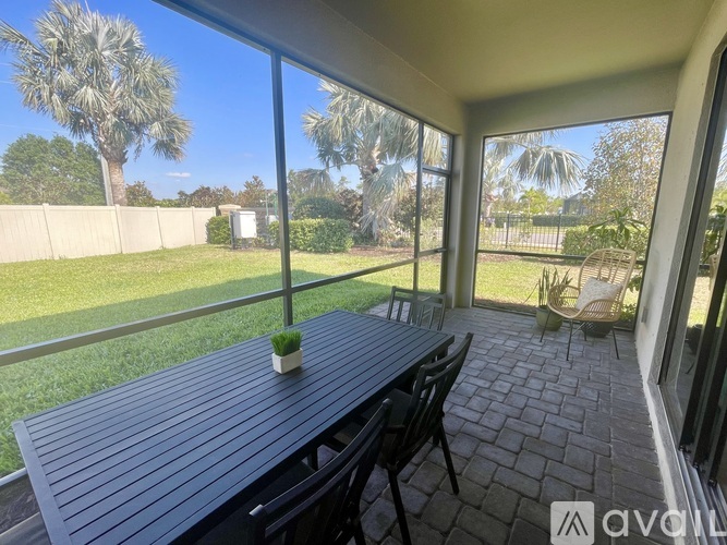 A patio with a table and chairs overlooking a grassy area.