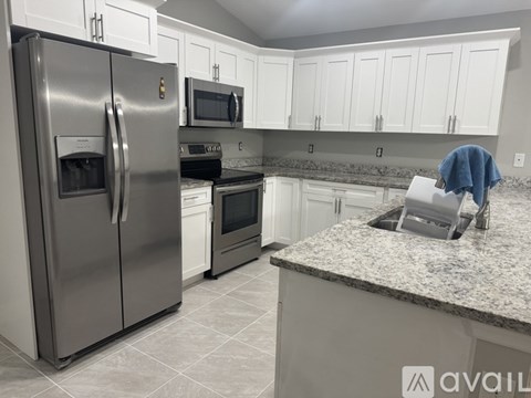 A kitchen with a stainless steel refrigerator and a granite countertop.