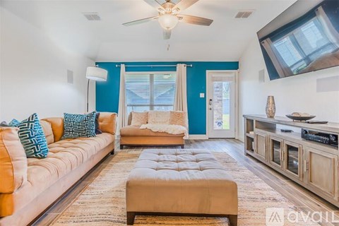 A living room with a beige couch and a brown ottoman.