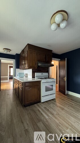 A kitchen with wooden cabinets and a white stove top oven.