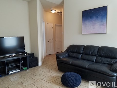 A living room with a black leather couch and a television.