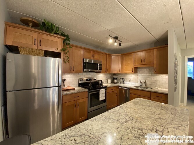 A kitchen with wooden cabinets and a marble countertop.