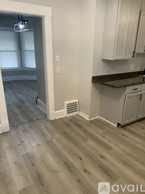A kitchen with white cabinets and a wooden floor.