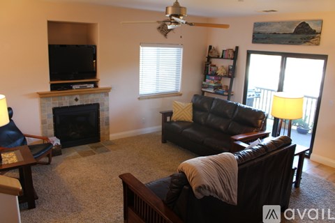 A living room with a black leather couch and a television.