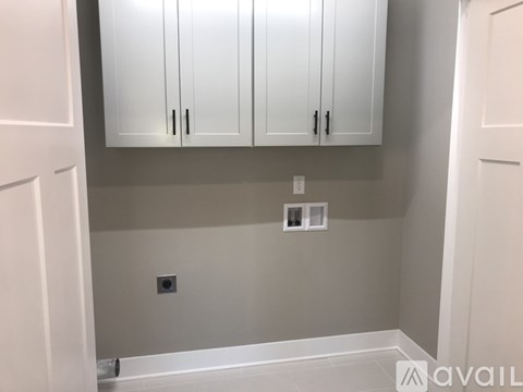 A kitchen with white cabinets and a grey wall.
